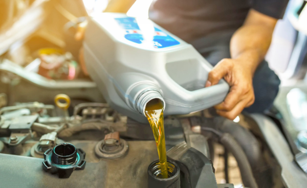 Car mechanic replacing and pouring fresh oil into engine at maintenance repair service station.